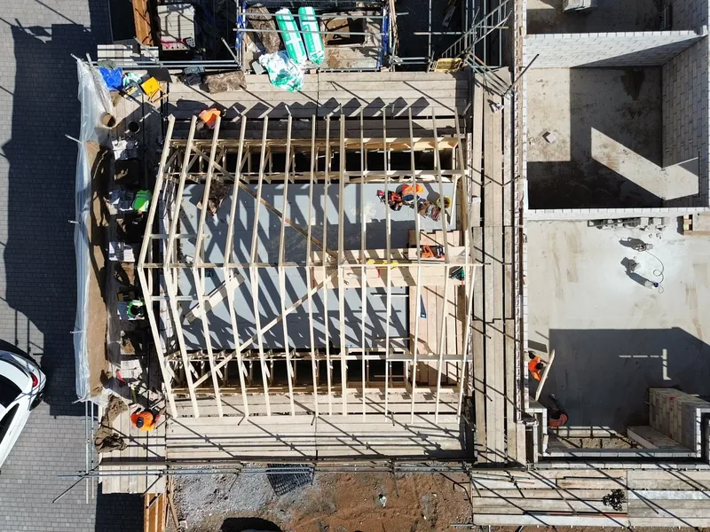 Overhead drone view of timber roof trusses erected on a scaffolded new build plot