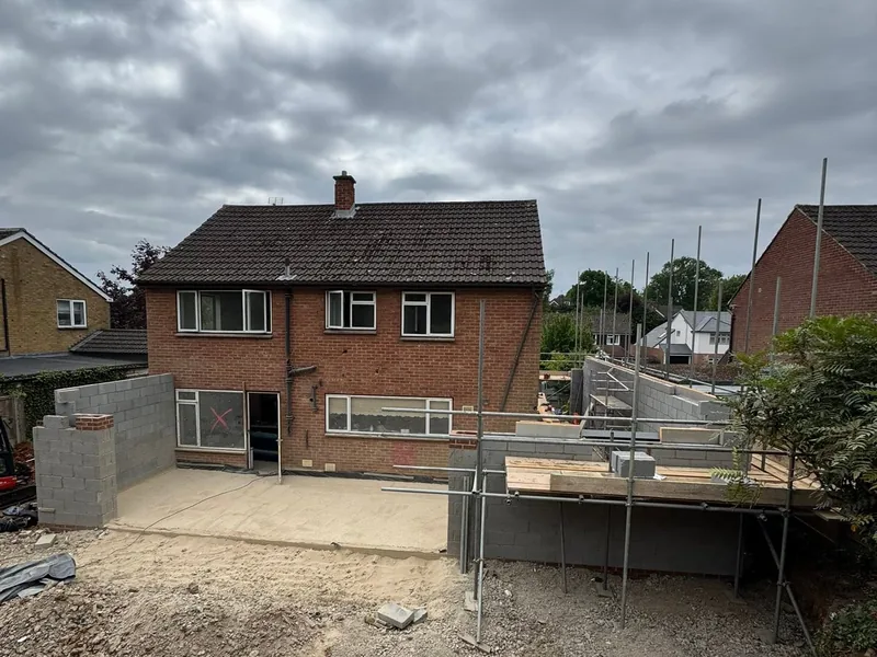 Brick house with a new blockwork extension under construction and scaffolding in place