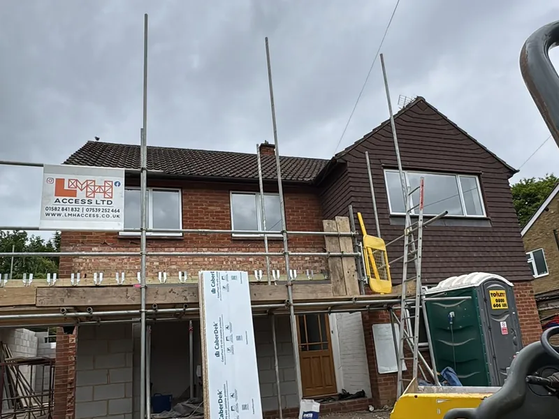 Scaffolded house elevation with existing cladding to the gable ahead of replacement