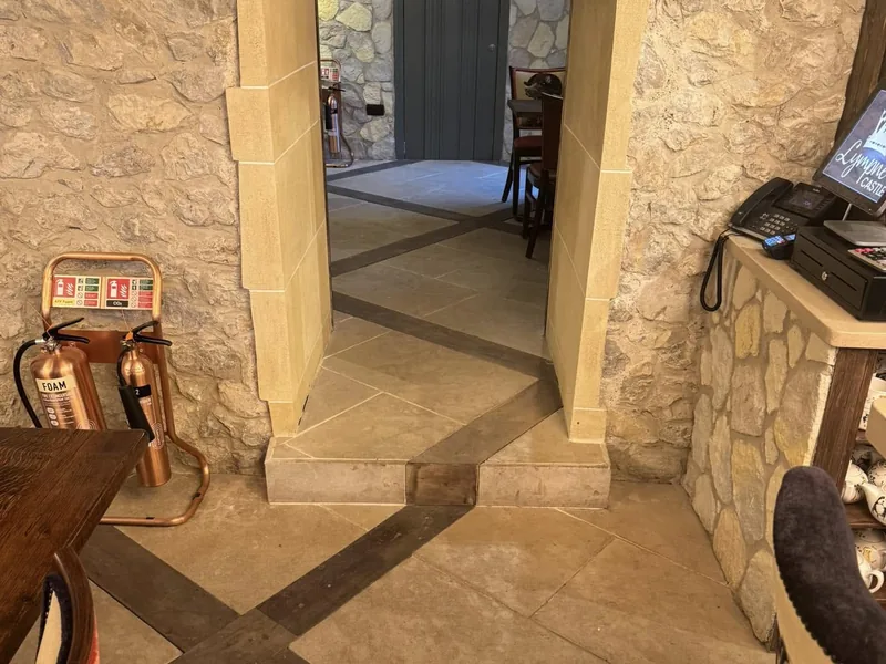 Stone walled interior with a flagstone floor and doorway through to a dining area