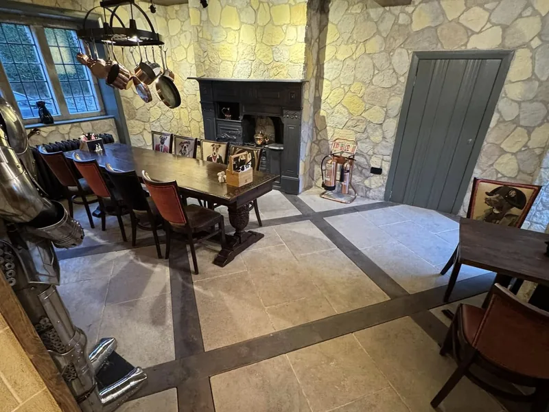 Dining area with a large stone fireplace, timber table and chairs in a stone walled room
