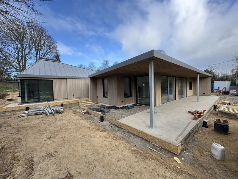 Timber clad single storey building with a standing seam metal roof nearing completion