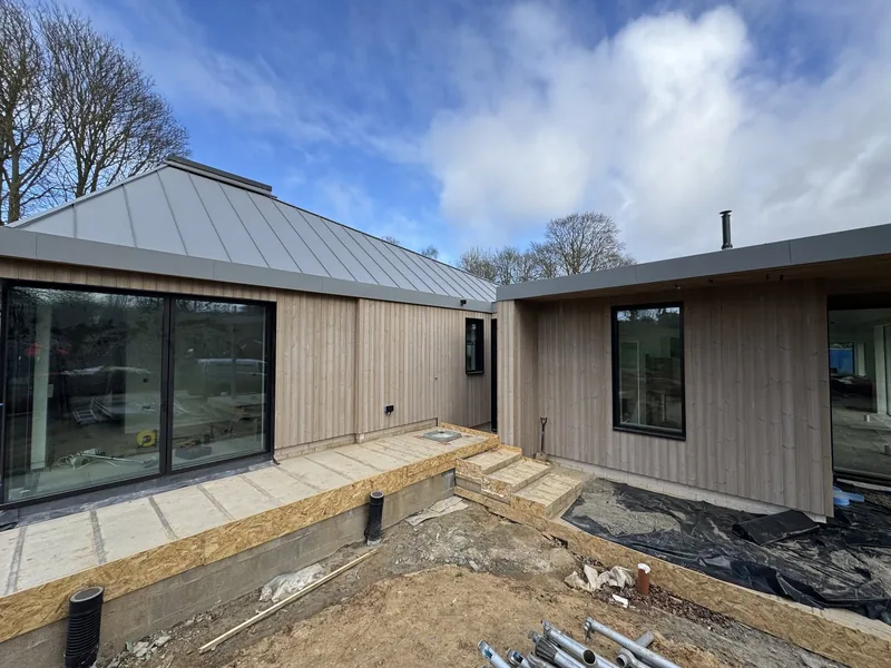 Timber clad elevation with large windows under a standing seam metal roof
