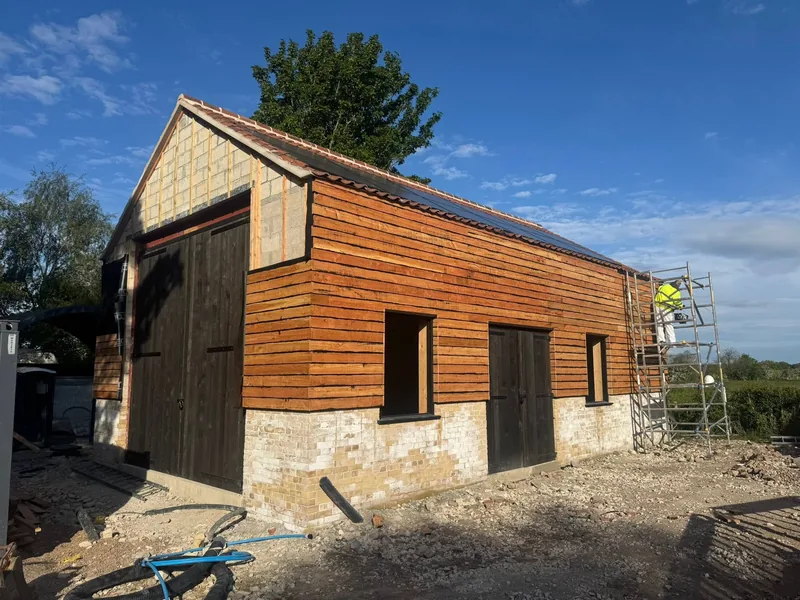 New timber cladding fixed above the stone walls of a barn with large timber doors