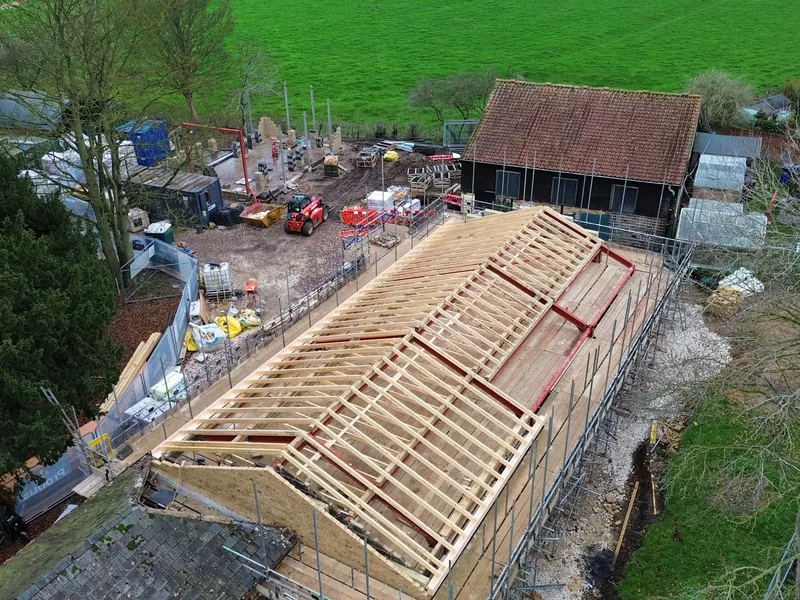 Aerial view of a new timber roof structure on red steel beams beside an older tiled building