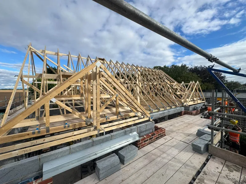 Prefabricated trusses standing on the wall plate at scaffold level on the Boston house
