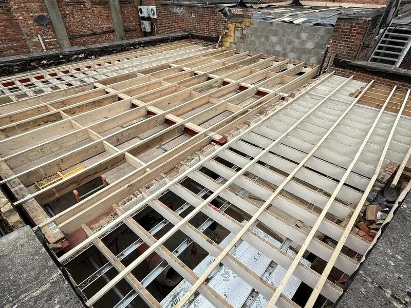 Timber flat roof joists and firrings spanning a town centre unit before decking