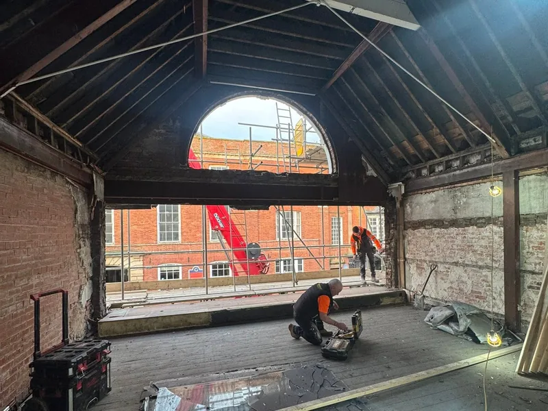 Stripped interior with exposed roof timbers and a large arched opening during a conversion