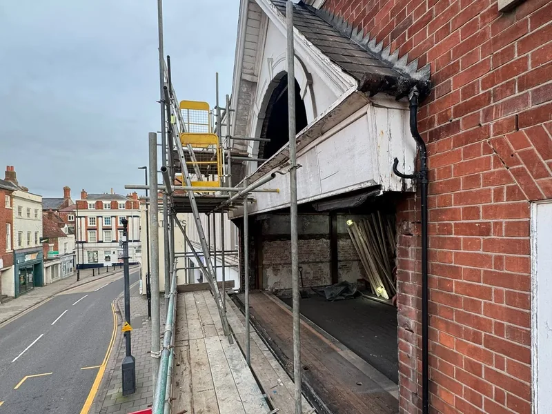 Scaffolded brick frontage with an arched opening above a high street