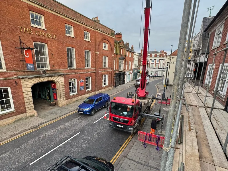Lorry mounted crane working on a high street outside a Georgian brick building