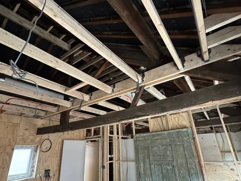 New timber joists installed alongside original beams inside a building conversion