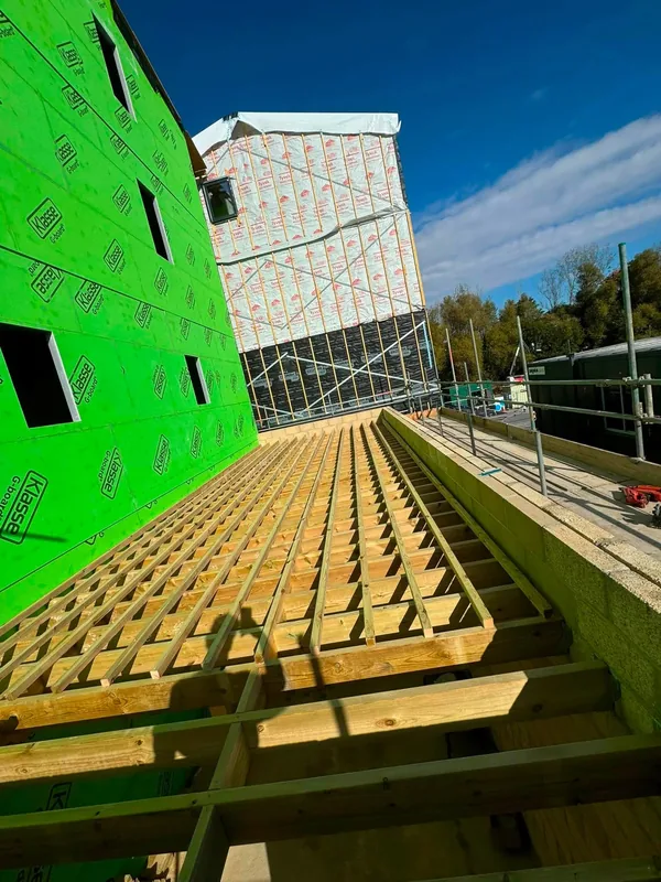 8x2 treated joists at 300mm centres on the cycle store roof, beside a building wrapped in green sheathing
