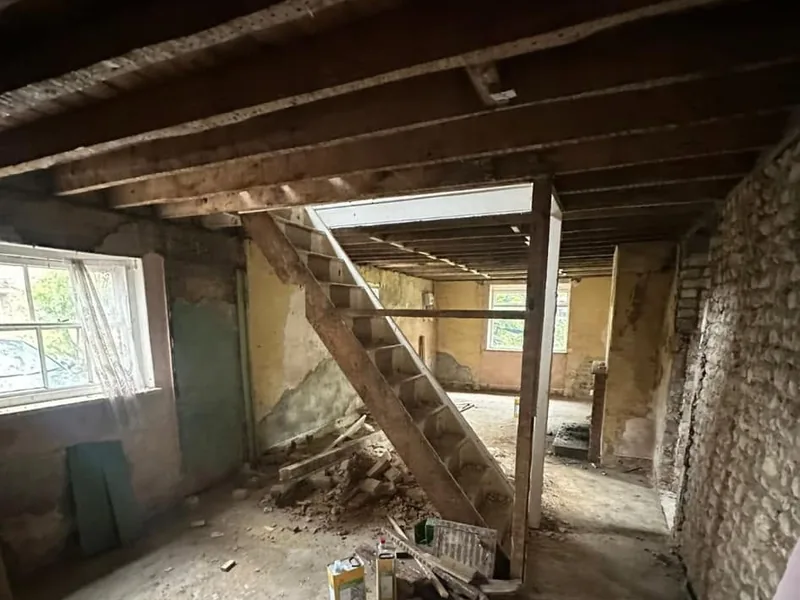 Stripped interior with an old timber staircase and exposed ceiling beams