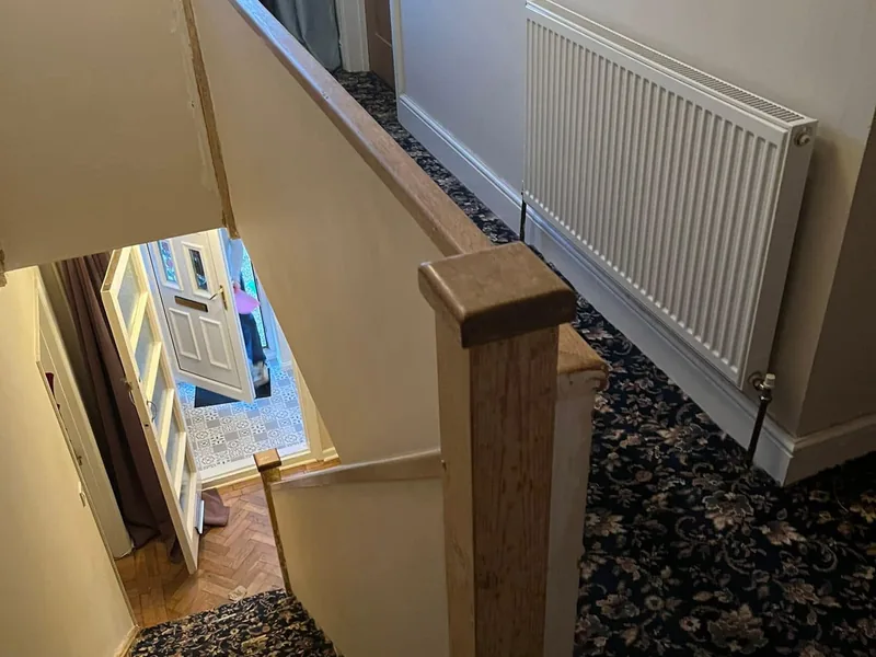 Oak newel post and handrail on a landing above a hallway