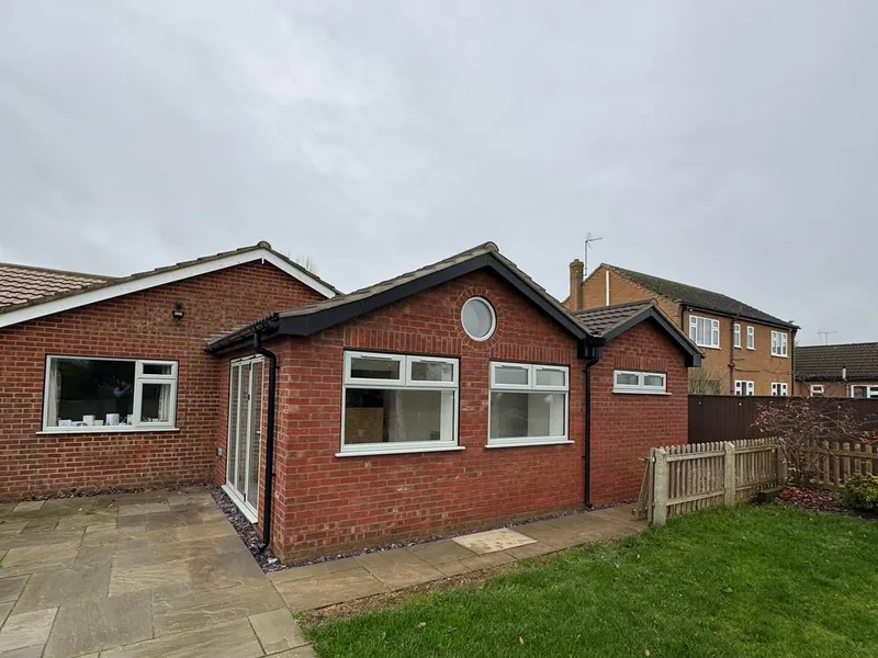 Rear of a single storey brick extension with new windows and a paved patio