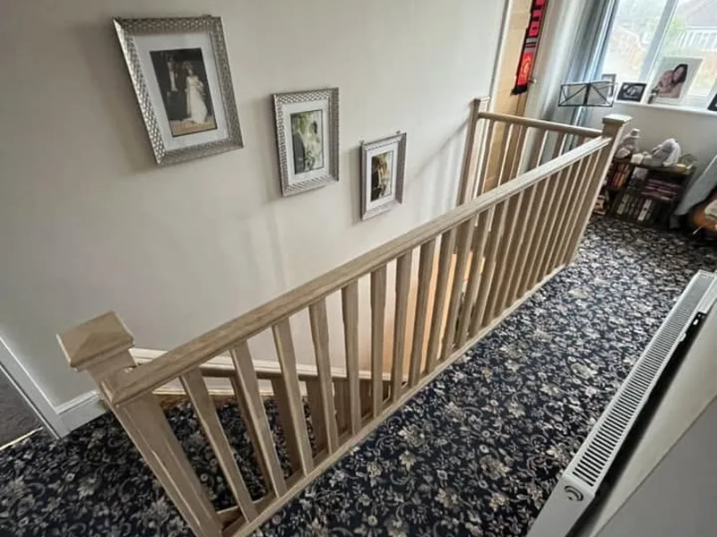 Timber landing balustrade with spindles beside framed photographs