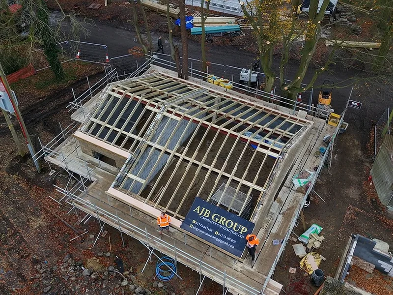 Aerial view of new timber joists spanning a blockwork structure with an AJB Group banner