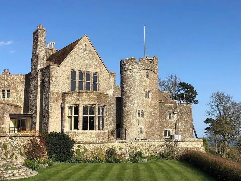 Historic stone castle with a round tower and manicured lawn