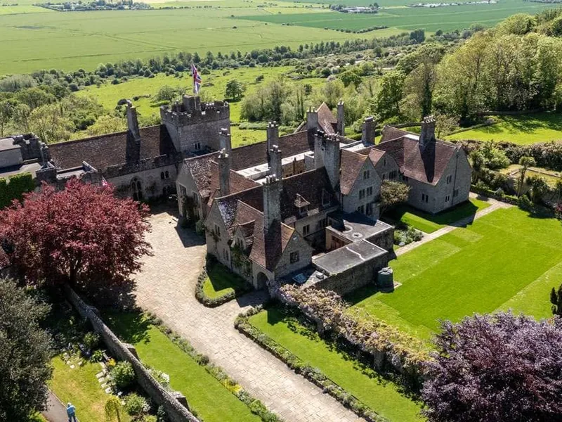 Aerial view of a historic castle and its tiled roofs with gardens and countryside beyond
