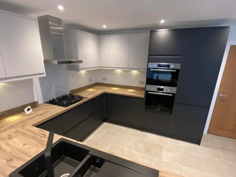 Two tone kitchen with white wall units, dark base units, extractor hood and built in double oven
