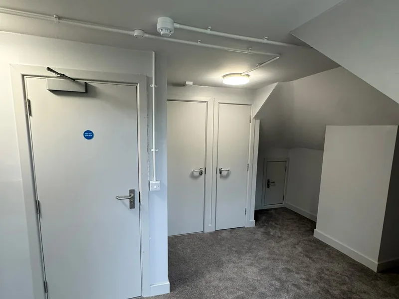 Completed internal door set with overhead closer and lever ironmongery in a corridor