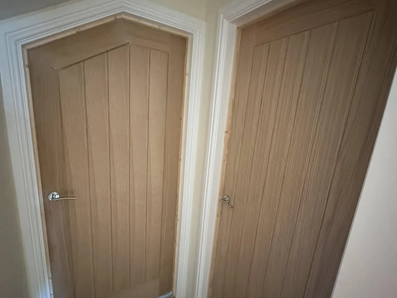 Newly hung light oak panelled internal doors in the corner of a finished room
