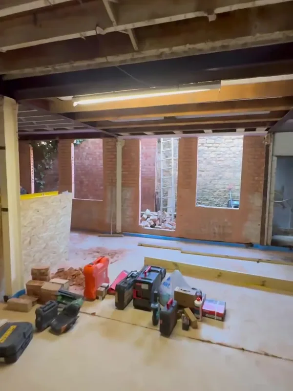 Carpenters setting out the ground floor of the Stamford warehouse, with pink fire board on site and openings in the rear wall