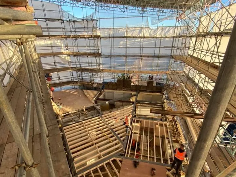 Looking down from scaffolding onto new timber joists and stud walls at roof level