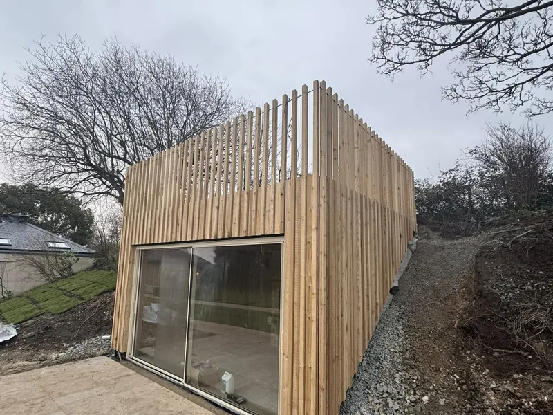 Single storey new build clad in vertical timber battens with large sliding glass doors