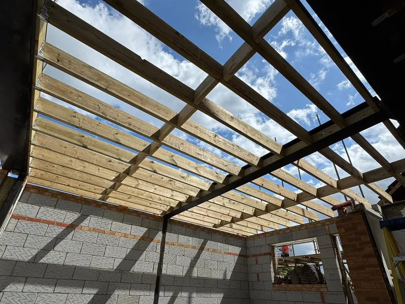 Looking up at new timber roof joists spanning the blockwork walls of an extension shell