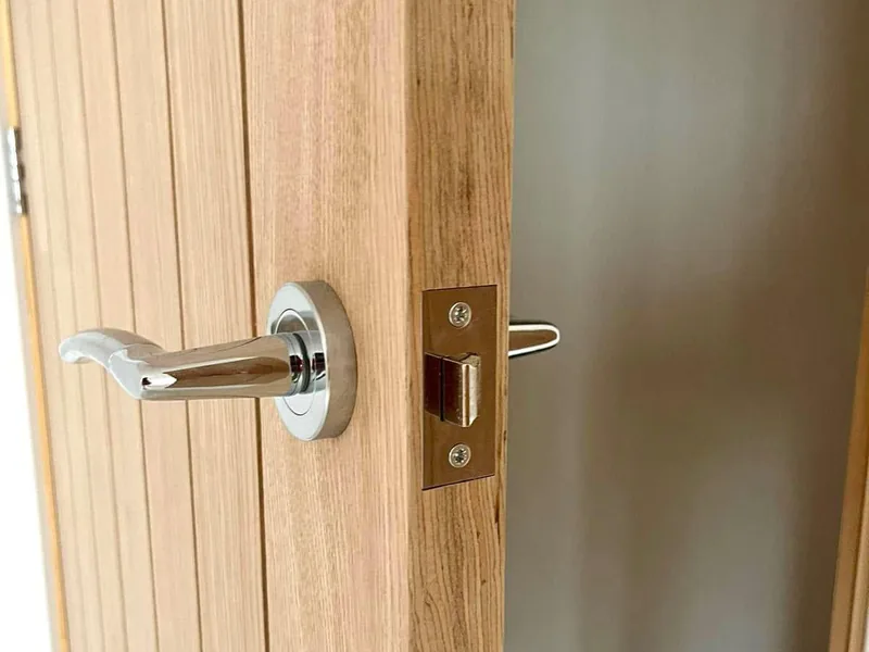 Close up of a chrome lever handle and latch keep fitted to an oak internal door