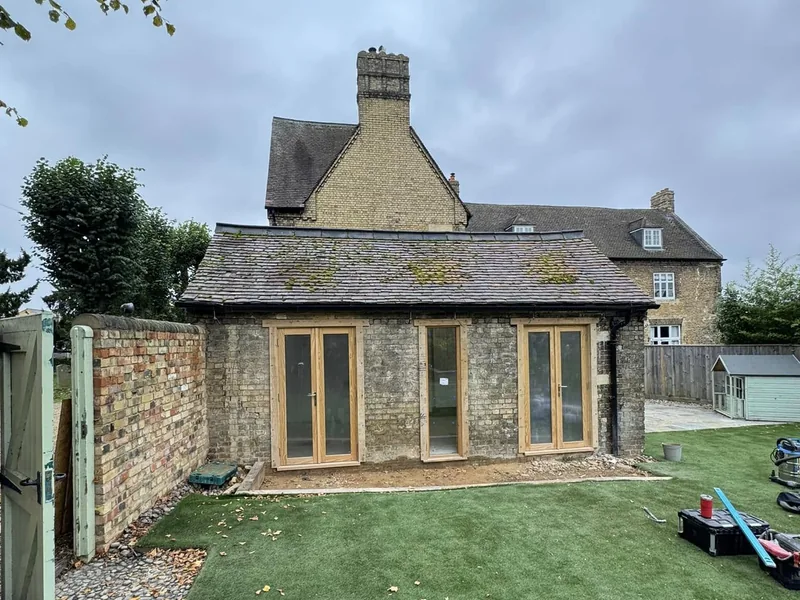 Three sets of new oak framed glazed doors fitted to a stone outbuilding with a tiled roof