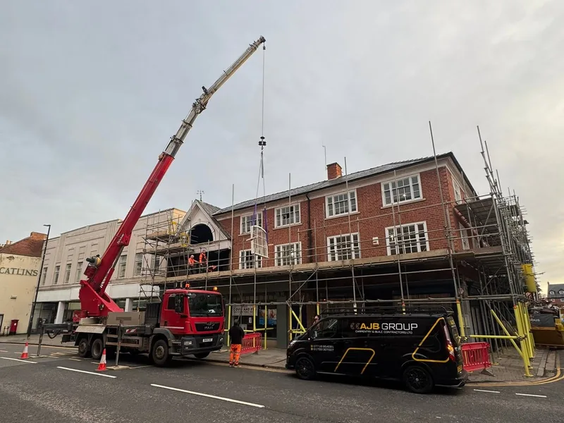 Mobile crane and AJB Group van outside a scaffolded town centre building