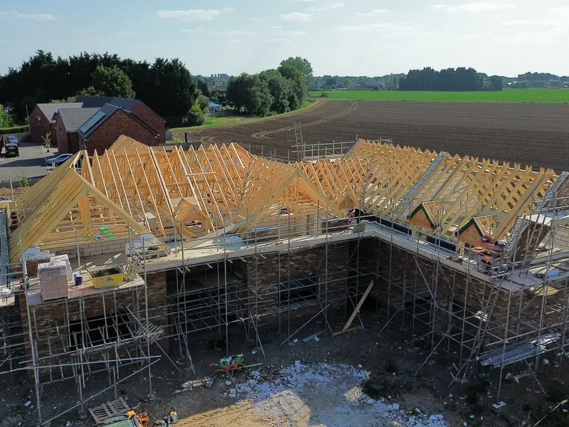 Aerial view of new timber roof trusses and framed dormers over a scaffolded new build