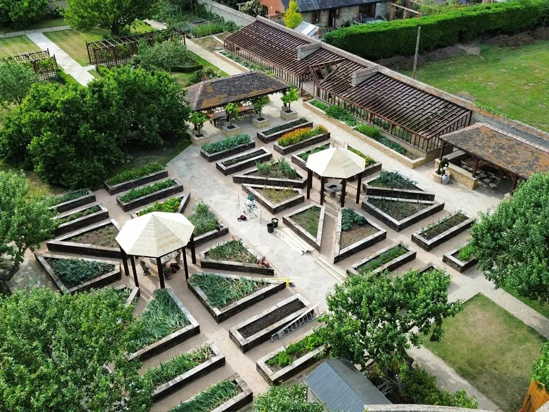 Aerial view of a formal garden with raised timber beds, gravel paths and parasols