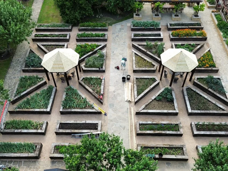 Aerial view of a formal kitchen garden with raised beds, gravel paths and two parasols