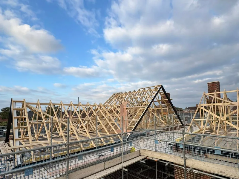 New timber roof trusses forming the gable and hip ends of a scaffolded roof