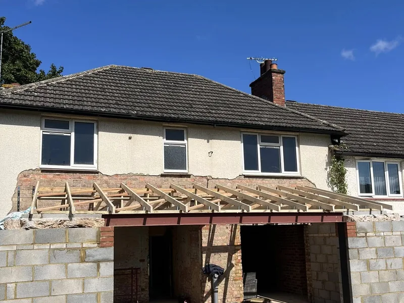 New timber lean to roof rafters over a blockwork extension shell on a rendered house