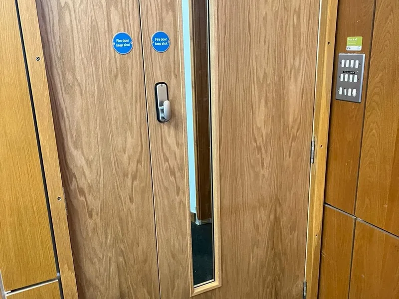 Double fire doors with vision panel and keep shut signage in a commercial corridor