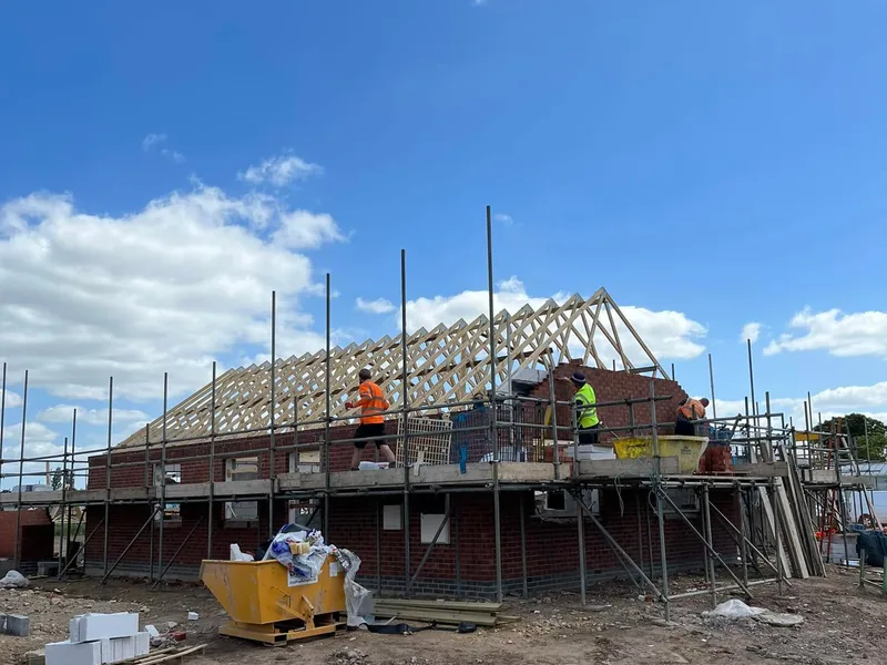 Roof trusses being erected on a new build house with scaffolding and site workers