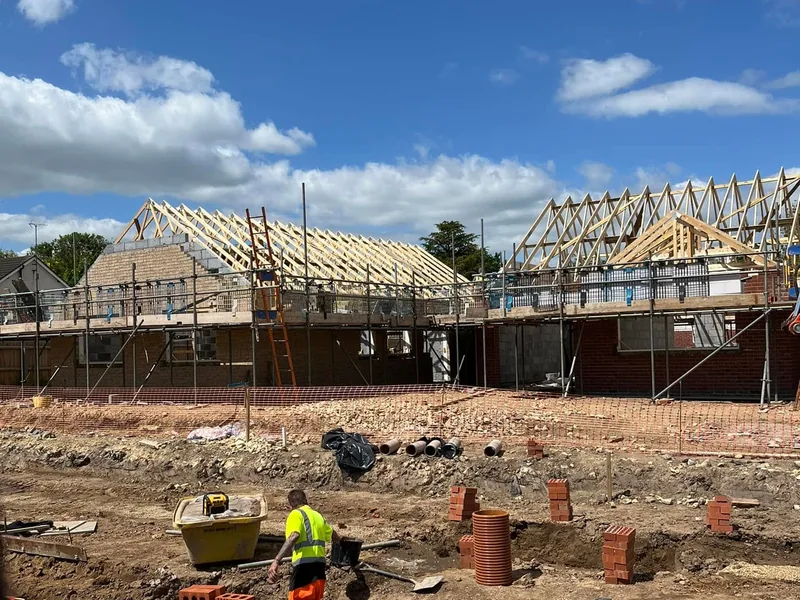 Roof trusses erected on new build houses with scaffolding and groundworks in the foreground