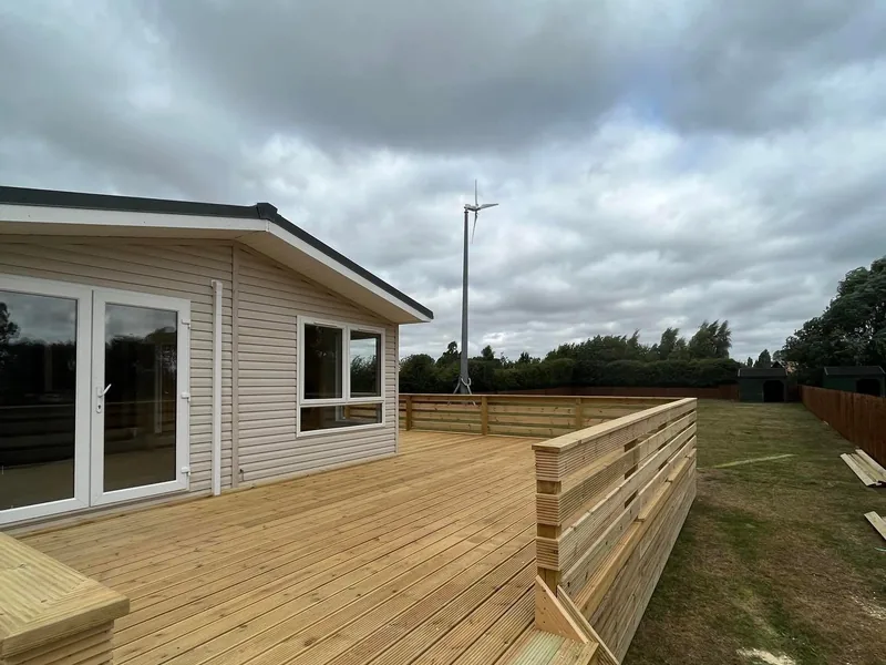 New timber decking with a slatted balustrade built around a clad lodge
