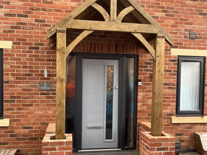 Oak framed porch canopy over a grey composite front door on a red brick house