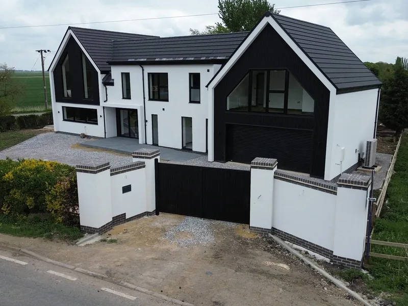 Modern rendered new build house with dark gables, black windows and boundary walls