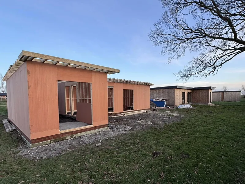 Single storey timber framed lodge sheathed out with roof joists fitted and a completed lodge behind