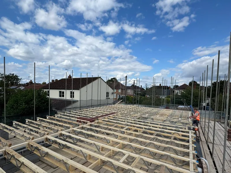 Metal web joists laid at close centres to form a first floor with a carpenter working on the deck