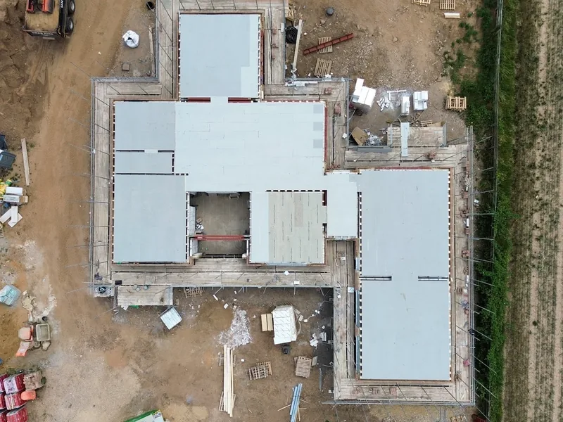 Overhead view of a new build ground floor with insulation boards laid inside the blockwork walls