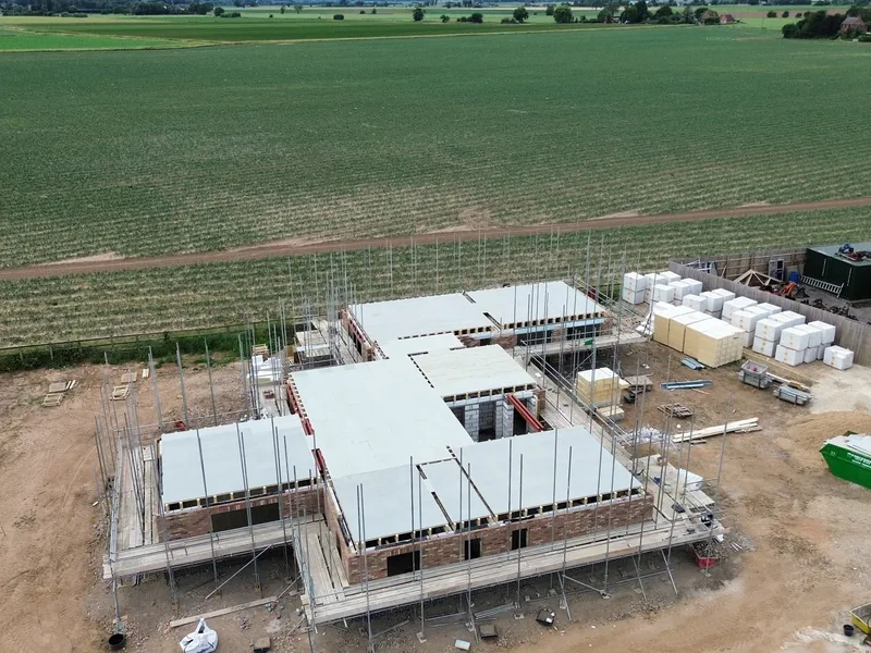 Aerial view of a new build with the first floor deck laid over brickwork and scaffolding around it