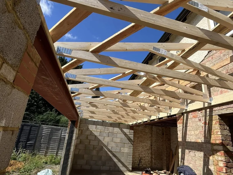 New timber roof rafters fixed between blockwork walls and an existing brick building
