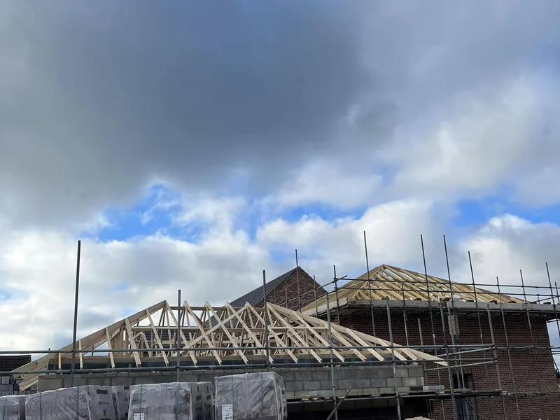 Trusses being craned into position and braced on a house plot